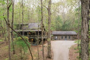 A cabin with a large deck and a separate building, surrounded by a forest. - Gym, Sauna, Spa, Firepit, Game Room + Playground! (Fannin County)