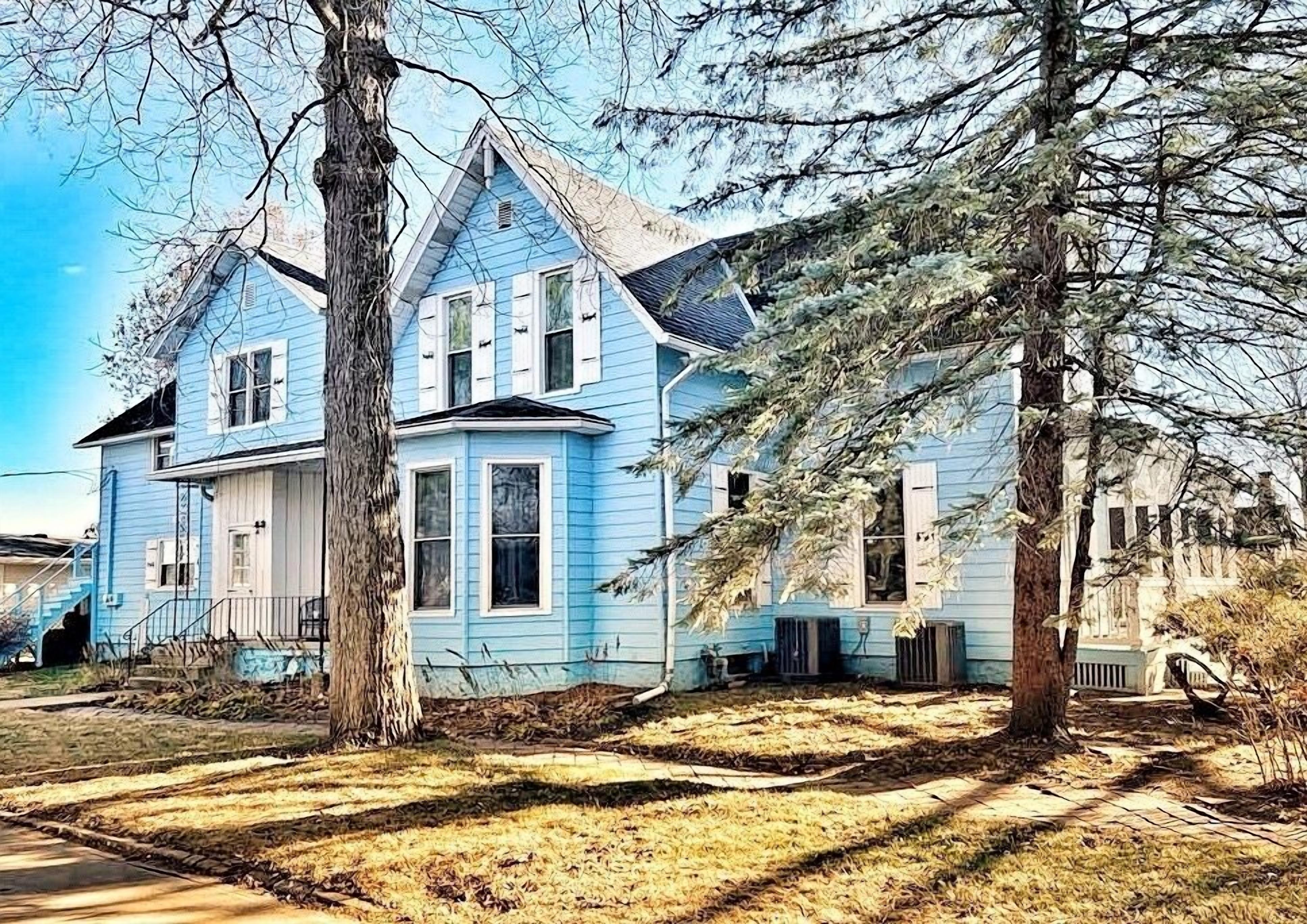 A two-story house with a prominent tree in front.