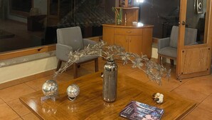 A wooden dining table with decorative glassware, a vase, and a book.
