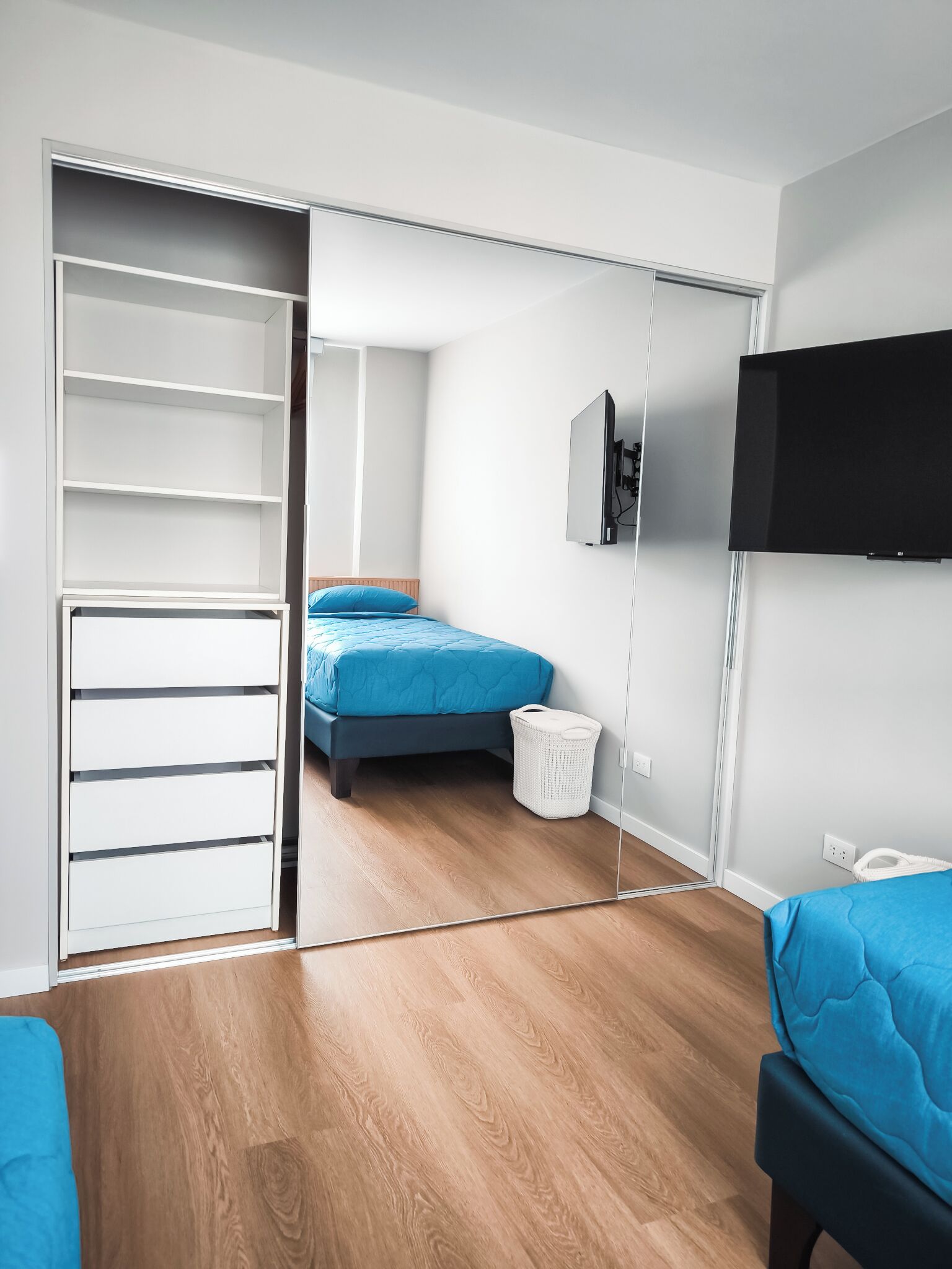 Quarto com cama, guarda-roupa, televisão e espelho.