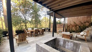 An outdoor patio area with stone flooring, wooden furniture, and a hot tub. - Cabaña Cedro, alojamiento boutique en Avándaro (Valle de Bravo)