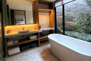 A modern bathroom with a freestanding bathtub, a large mirror, and a stone wall. - Cabaña Cedro, alojamiento boutique en Avándaro (Valle de Bravo)