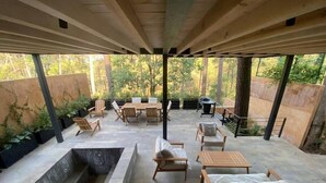 Een terras buiten met een jacuzzi, houten meubels en uitzicht op bomen.