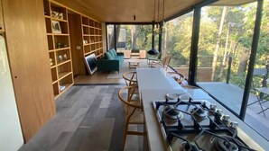Een moderne keuken met een groot raam, houten planken, een groene bank en een eethoek.
