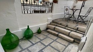Una escalera de piedra que lleva a una pared blanca con una reja de metal.