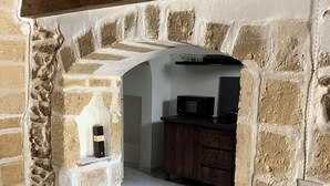 Un arco de piedra que da acceso a una cocina con microondas y armarios de madera.