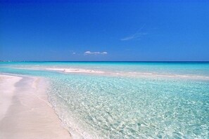 A beach with clear turquoise water and white sand.
