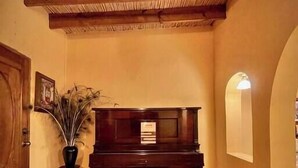 A room with a wooden piano, a small table with a vase, and a door. - Casa en Parras de la Fuente (Parras de la Fuente)