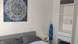 A bedroom with a bed, a bedside table, a wall-mounted shelf, and a wardrobe. - Departamento en Tequesquitengo (Tequesquitengo)