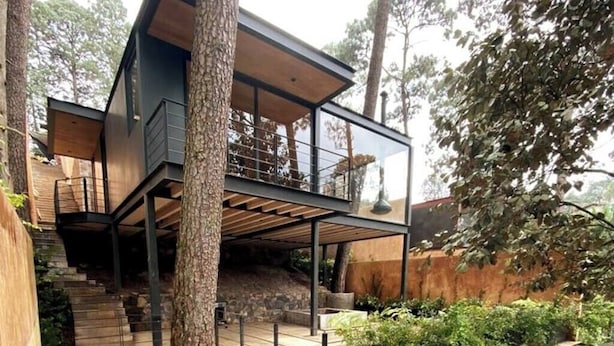 Une maison moderne avec un escalier en bois menant à un balcon.