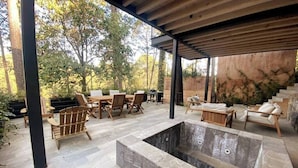 Un espace extérieur aménagé en terrasse, avec un sol en pierre, des meubles en bois et un jacuzzi.
