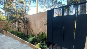 A gated entrance with a concrete wall and a stone pathway leading to a lush garden area. - Suite Oyamel en Valle de Bravo (Valle de Bravo)