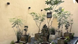 Ein Innenhof mit in einem geometrischen Muster angeordneten Pflanzkübeln, umgeben von einer Steinbordüre und einem gefliesten Boden.