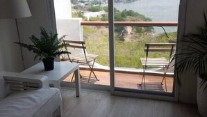 A balcony with a view of a river and greenery. There is a white table with a potted plant and two chairs. - Depto con Alberca y Vista al Lago en Teques (Tequesquitengo)