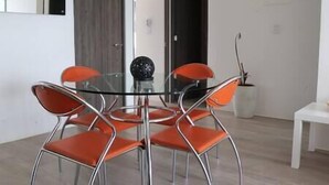 A modern dining area with a glass table surrounded by four orange chairs. - Depto con Alberca y Vista al Lago en Teques (Tequesquitengo)