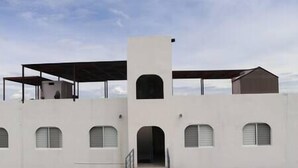 A modern building with a central entrance, multiple windows, and a covered upper level. - Depto con Alberca y Vista al Lago en Teques (Tequesquitengo)
