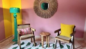 Ein Zimmer mit zwei Holzstühlen, einem kleinen runden Tisch, einer grünen Stehlampe und einem Spiegel an der Wand.