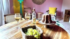 Ein Esstisch mit Kuchen, zwei Weingläsern, einer Flasche und einem Korb voller Trauben.