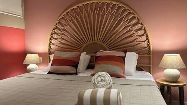 Ein Hotelzimmer mit einem Bett, Kissen, einem Kopfteil und zwei Nachttischlampen.