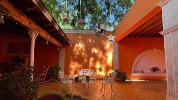 A courtyard with a tiled floor, a table with chairs, and potted plants.