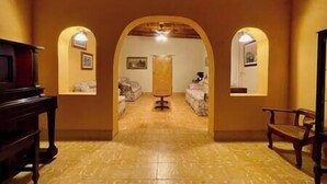 A hallway with a tiled floor, arched doorways, and a central column.