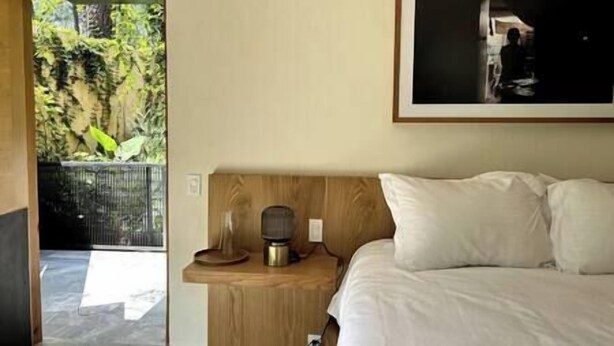 A bedroom with a bed, a wooden nightstand, a framed picture on the wall, and a view of greenery outside. - Suite Cedro, Cabaña Boutique en Valle de Bravo (Valle de Bravo)