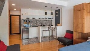 A compact living space with a kitchenette, a dining area with two chairs, and a small seating area with a sofa and a chair. - Loft Chic en el Corazón de la CDMX Centro (Cuauhtémoc)