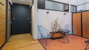 A modern interior with a wooden floor, a black door, and two blue wire chairs around a small table with a plant. - Loft Chic en el Corazón de la CDMX Centro (Cuauhtémoc)