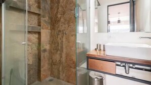 A modern bathroom with a glass shower enclosure, a wooden vanity with a sink, and a mirror above the vanity. - Moderno Loft en el Centro Histórico CDMX (Cuauhtémoc)