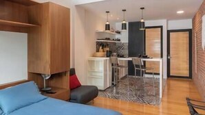 A modern living room with a sofa, a dining area with a table and chairs, and a kitchen with hanging lights. - Moderno Loft en el Centro Histórico CDMX (Cuauhtémoc)