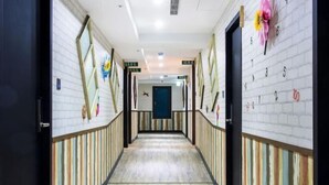 A hotel corridor with striped walls, a wooden floor, and a blue door at the end. - RF Hotel - Sanchong (New Taipei City)