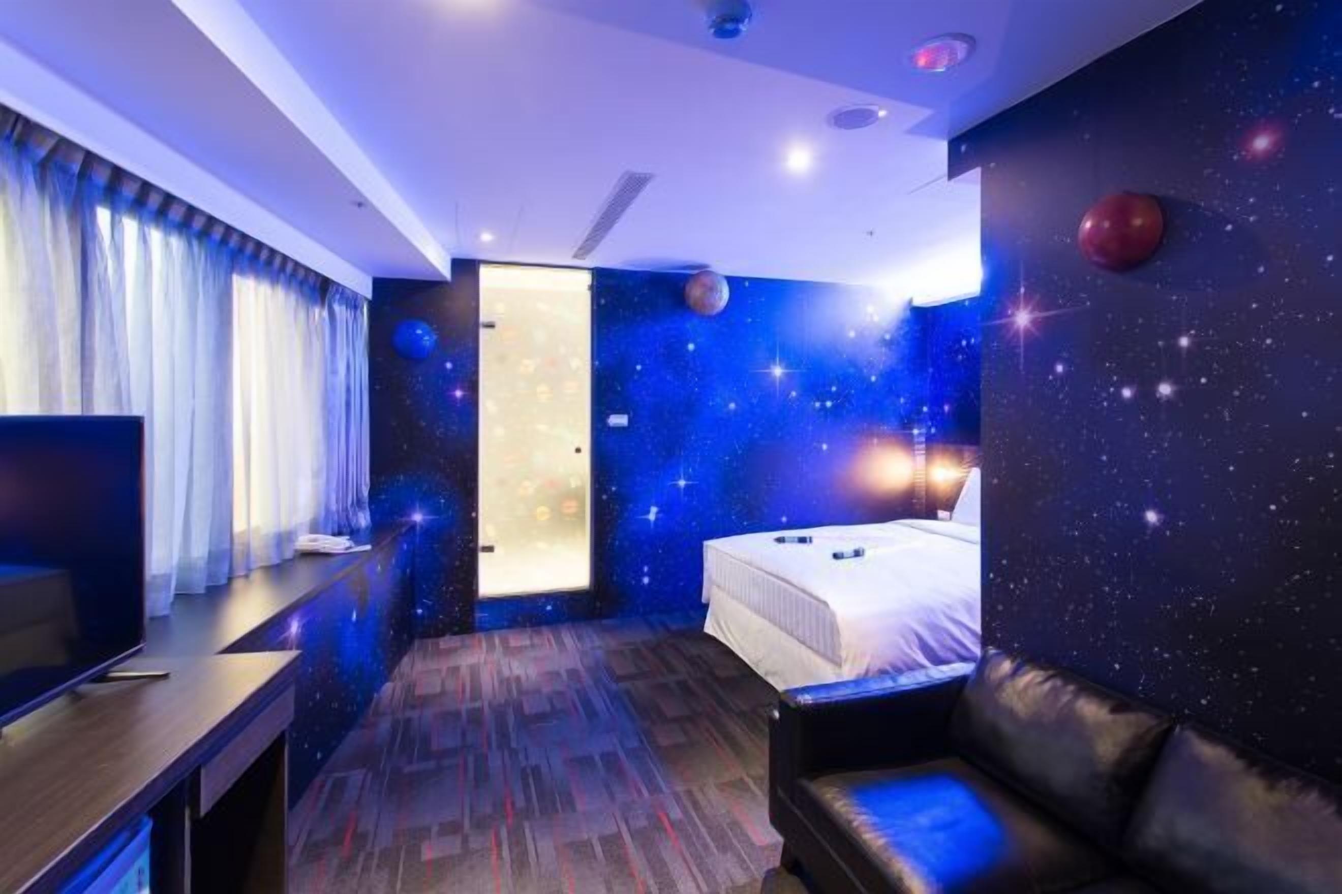 Une chambre d’hôtel avec un lit, une télévision, un bureau et un canapé en cuir.