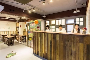 A reception desk with staff, wooden tables, and a children's play area.