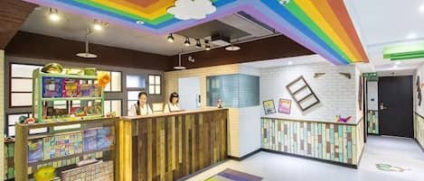 A children's play area with a rainbow ceiling, a play table, and a reception desk.