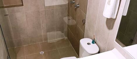 A modern bathroom with a shower, toilet, and sink.