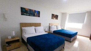 Ein Hotelzimmer mit zwei Betten, einem Nachttisch und einem Fenster mit Jalousien.