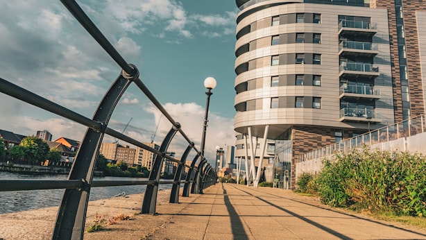 Une promenade en bord de mer, bordée d’un bâtiment moderne doté de balcons et d’une conception aux lignes courbes.