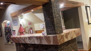 A stone counter with a marble top, a wooden ceiling beam, and a stone wall.