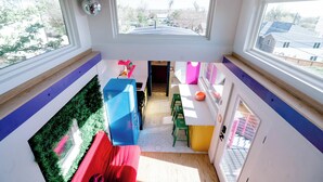 A modern kitchen with a blue refrigerator, a red sofa, and a green dining area. - One-of-a-Kind Renovated Train Caboose - Hot Tub - Games (Denver)