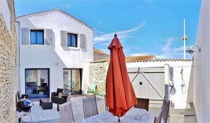 Enjoy a patio with outdoor seating, a table, and chairs, surrounded by a stone wall and a white fence.