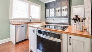 Een moderne keuken met roestvrijstalen apparatuur, een houten aanrecht en een spatwand met een geometrisch patroon.