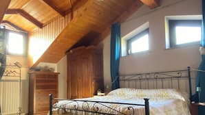 A bedroom with a wooden ceiling, a bed with a metal frame, a wooden chest of drawers, and a window with curtains. - The robin's garden - In the Piedmont countryside, your garden for relax! (Front)