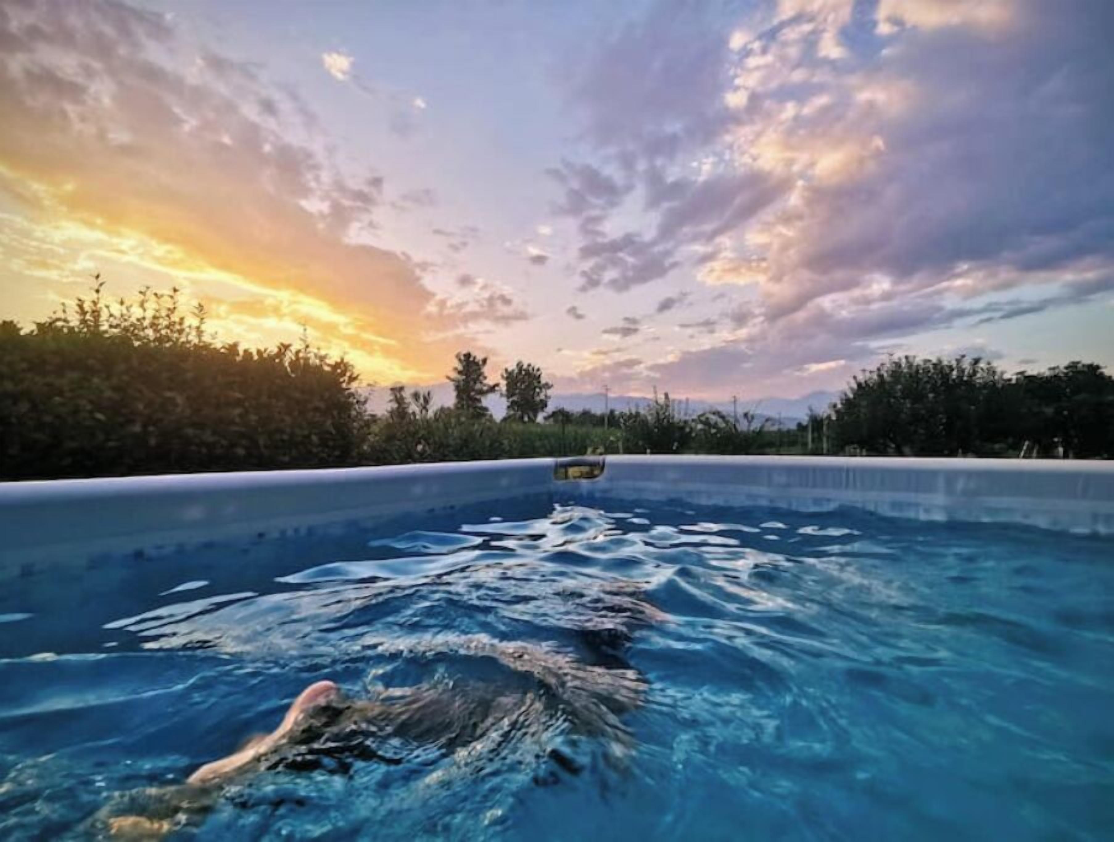 A swimming pool with clear blue water and a sunset in the background.