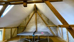 Een tafeltennistafel in een kamer met houten balken en een schuine kap.