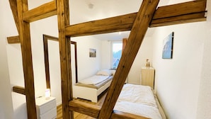 Een slaapkamer met een houten plafondconstructie, een bed, een nachtkastje en een dressoir.