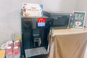 Una máquina de café con pantalla digital y un cartel que indica 'CAFÉ GRATIS'.