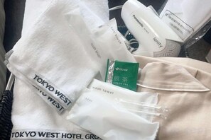 A collection of items including a white towel with 'TOKYO WEST HOTEL GROUP' text, a green tea sachet, and a white bottle with 'tonify' text. - Urban Hotel Tokyo Fuchu East Exit (Fuchu)