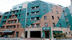A multi-story building with a green facade and a ground-level entrance.