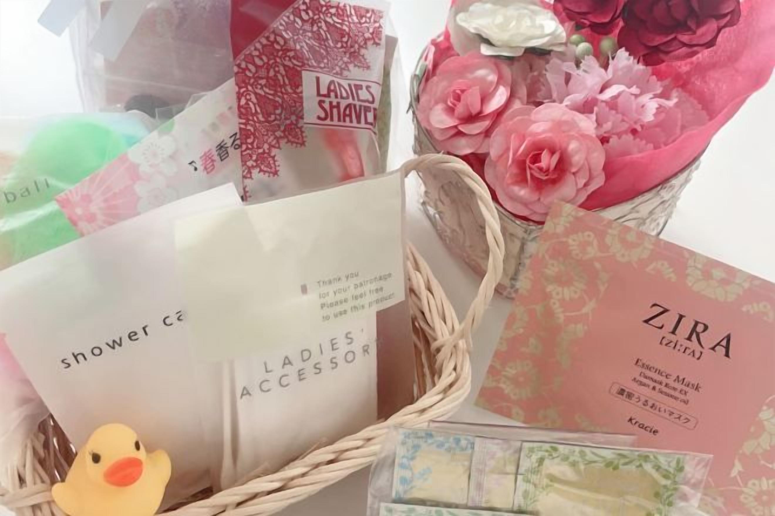 A basket with various items including a duck, a card, and some flowers.