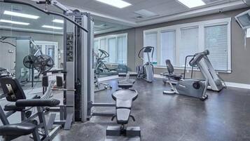 A gym with various exercise equipment, including treadmills, weight machines, and a bench.